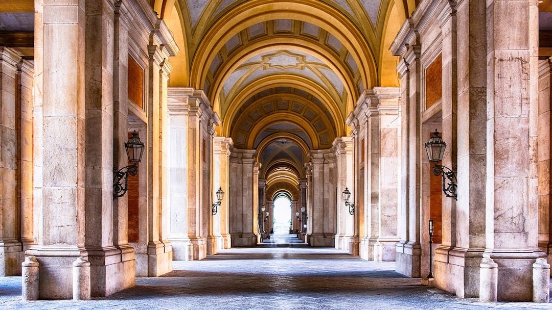 Royal Palace of Caserta interior with grand arched hallway and ornate columns.