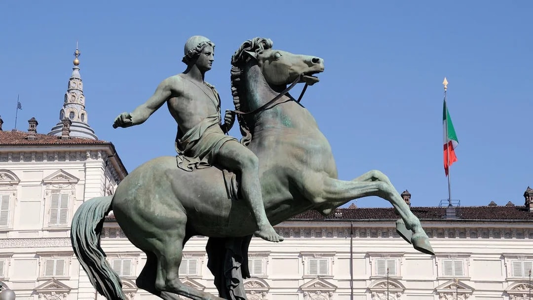 Equestrian statue in front of Royal Palace Museum, Turin, with Italian flag.