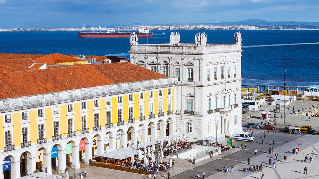Rua Augusta Arch overlooking Lisbon's waterfront with bustling square below.
