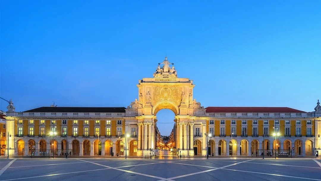 Arco da Rua Augusta in Lisbon at dusk, with illuminated arch and surrounding buildings.