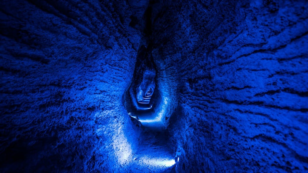 Ruakuri Cave illuminated passageway with textured rock walls, New Zealand.