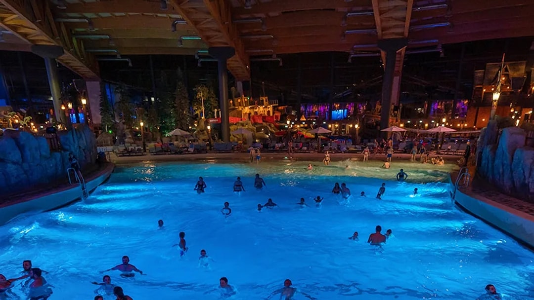 Indoor wave pool with people swimming at Rulantica water park, Germany.