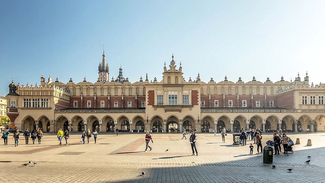MNK Sukiennice exterior with people walking in Kraków's main square.