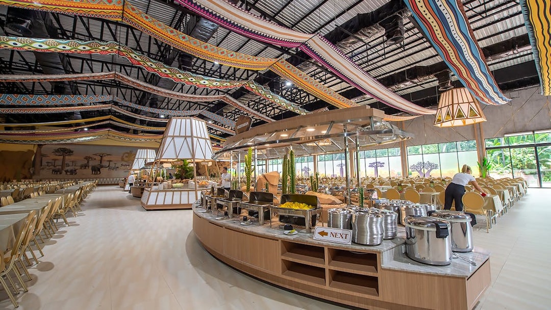 Buffet setup at Savanna restaurant in Safari World with colorful ceiling decor.