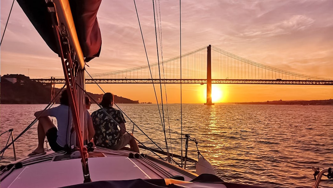 Sailing on the Tagus River at sunset with view of 25 de Abril Bridge in Lisbon.