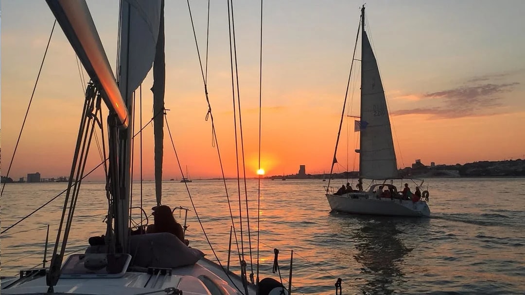 Sailboats on Tagus River at sunset during Lisbon cruise.