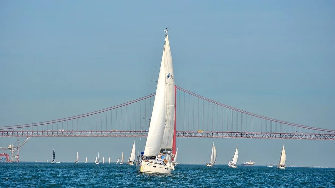 Sailboats on Tagus River with Lisbon's 25 de Abril Bridge in the background.