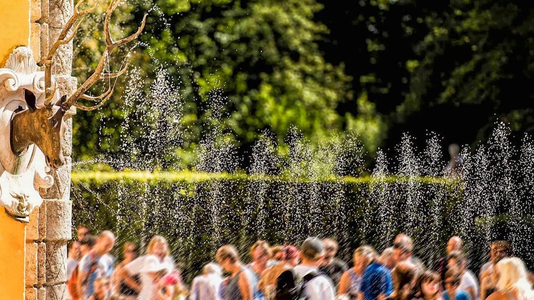 Visitors enjoying water trick fountains at Hellbrunn Palace, Salzburg.