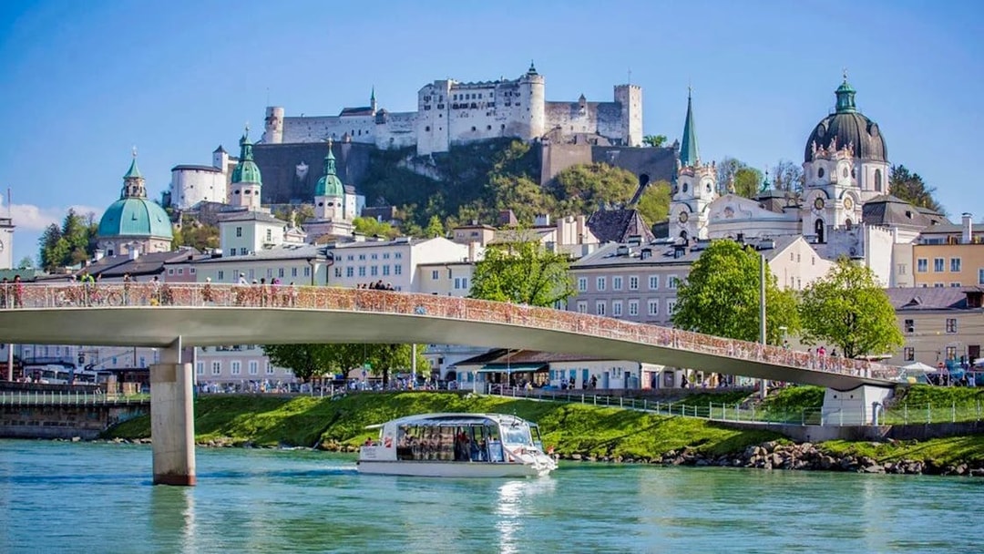 Salzburg city cruise boat on Salzach River with Hohensalzburg Fortress in the background.