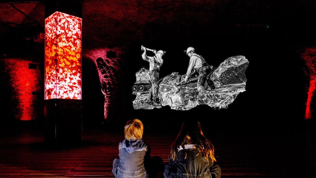 Children watching a salt mine exhibit in Salzburg with illuminated red pillars.