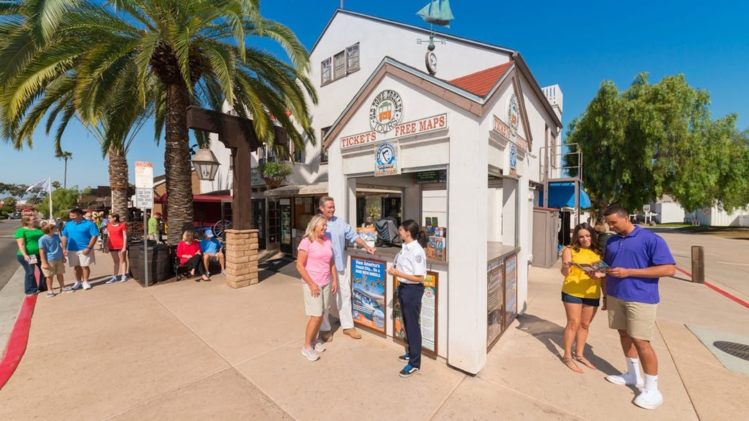 Ticket booth for Old Town Trolley Tour with people receiving maps and information.