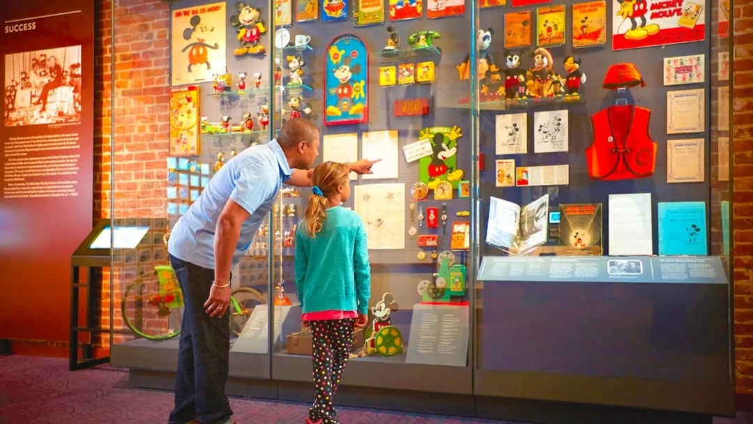 Father and daughter viewing Mickey Mouse exhibit at San Francisco museum.