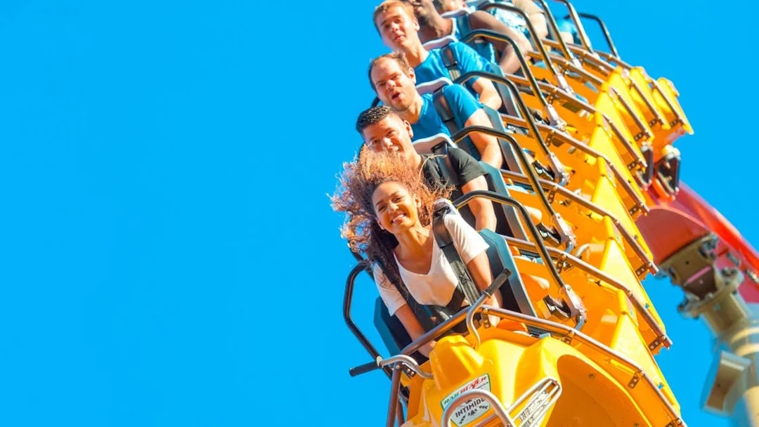 People enjoying a roller coaster ride in San Francisco with clear blue sky.