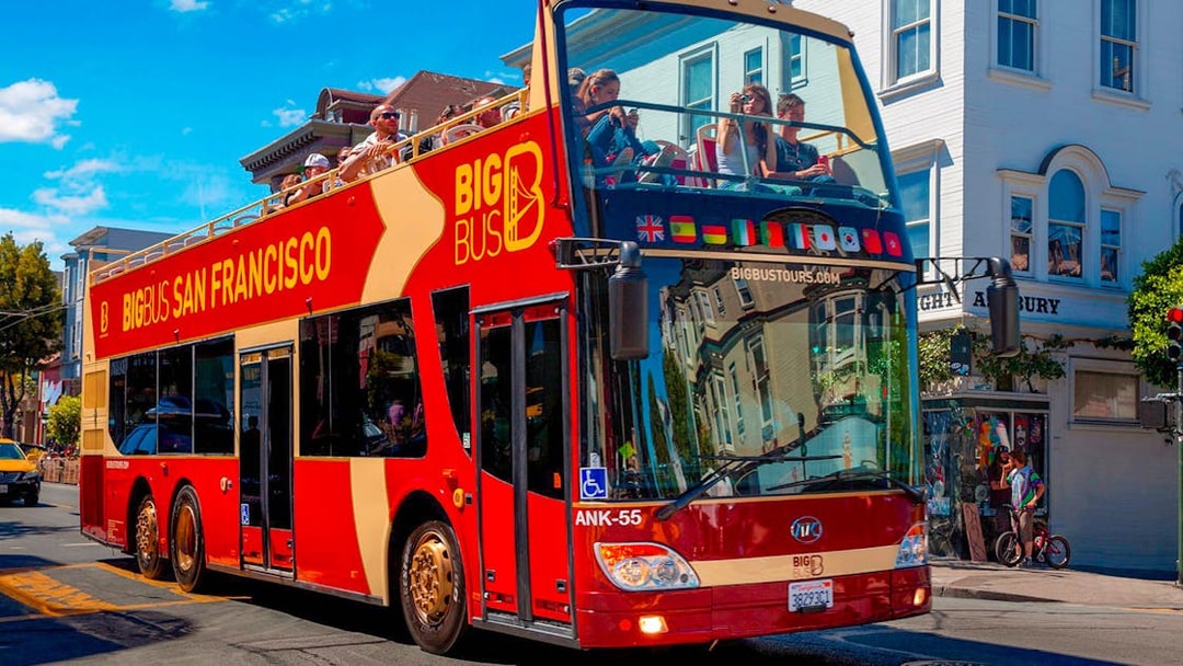 Open-top tour bus in San Francisco with passengers exploring city streets.