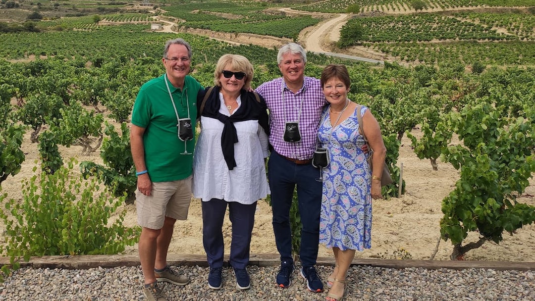 Group enjoying a vineyard tour in Rioja, Spain, with lush grapevines in the background.