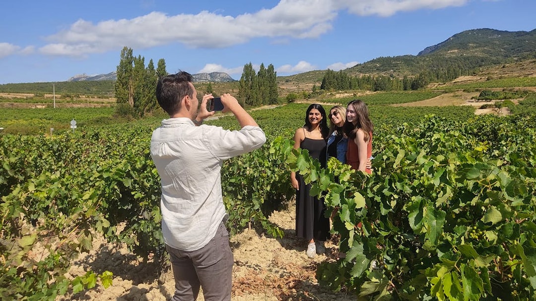 Tourists posing for a photo in a vineyard during a guided tour of Rioja wineries from San Sebastian.