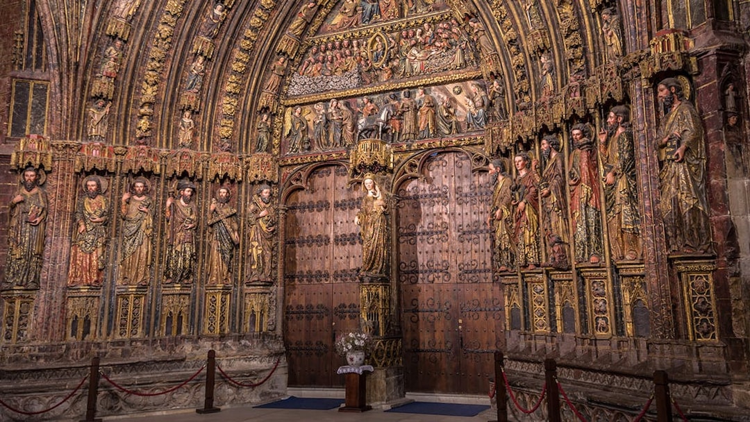 Ornate wooden door with detailed religious carvings in a historic Rioja winery.
