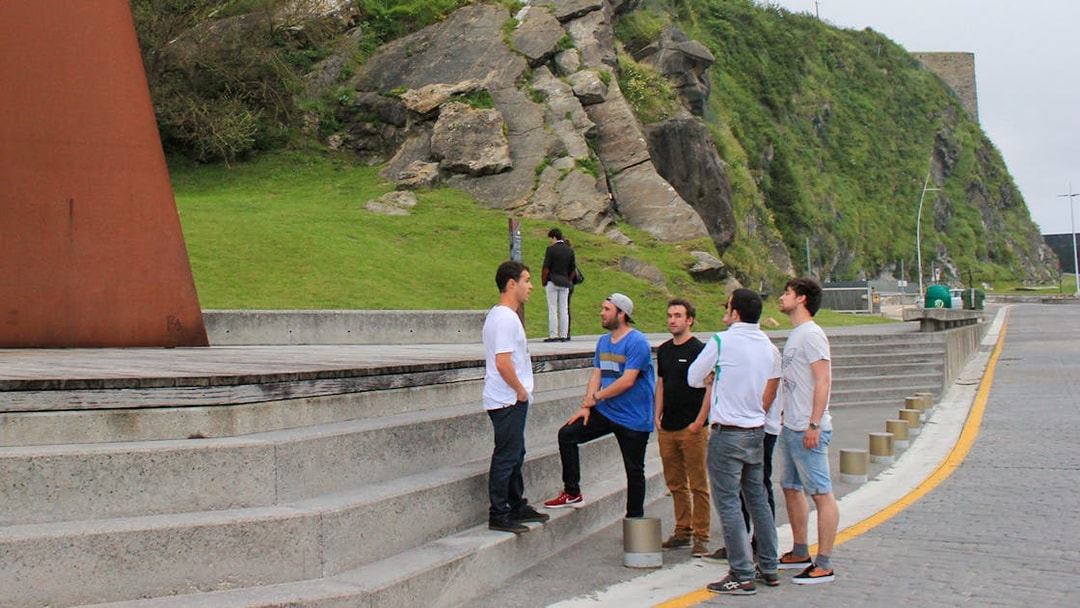 Group of tourists on a guided walking tour in San Sebastian near a modern sculpture.