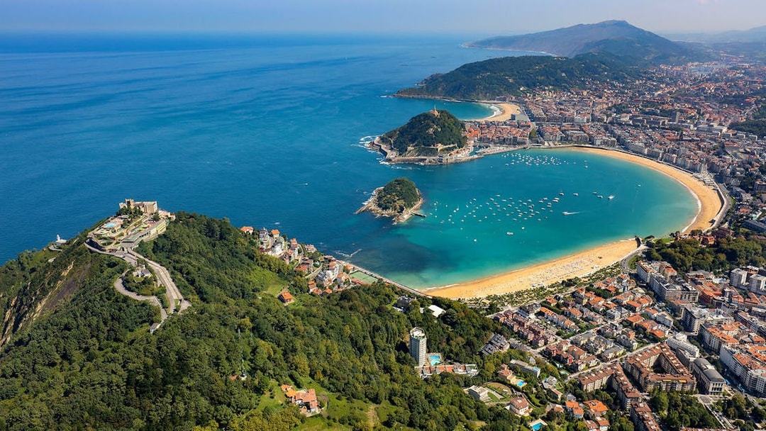 Aerial view of La Concha Bay in San Sebastian, Spain, with surrounding cityscape and coastline.