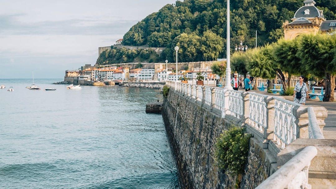 San Sebastian promenade with view of coastal buildings and lush hillside.