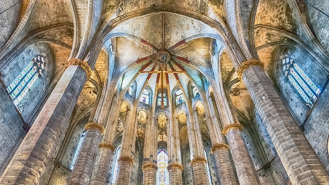 Interior view of Santa Maria del Mar's vaulted ceiling and stained glass windows.