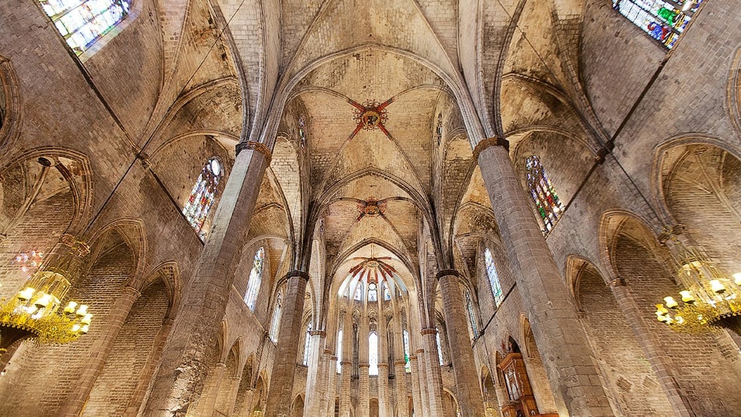 Interior view of Santa Maria del Mar's vaulted ceiling and stained glass windows in Barcelona.