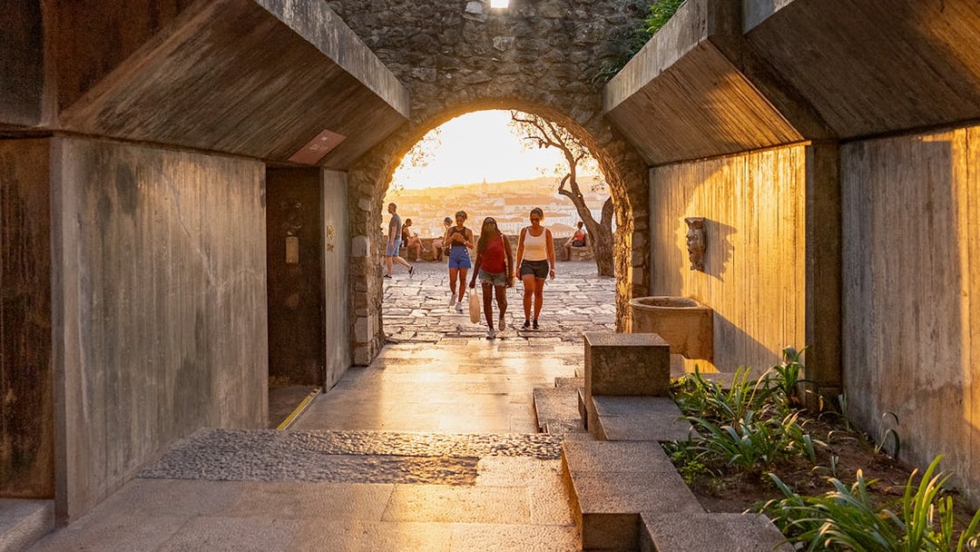 Visitors walking through an archway at St George's Castle during sunset.