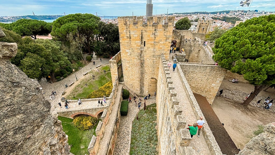 Top view of São Jorge Castle's entrance bridge with visitors walking along the stone path in Lisbon.