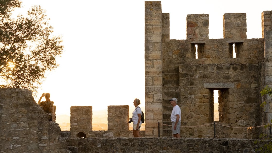 Visitors exploring St George's Castle with a guide at sunset.
