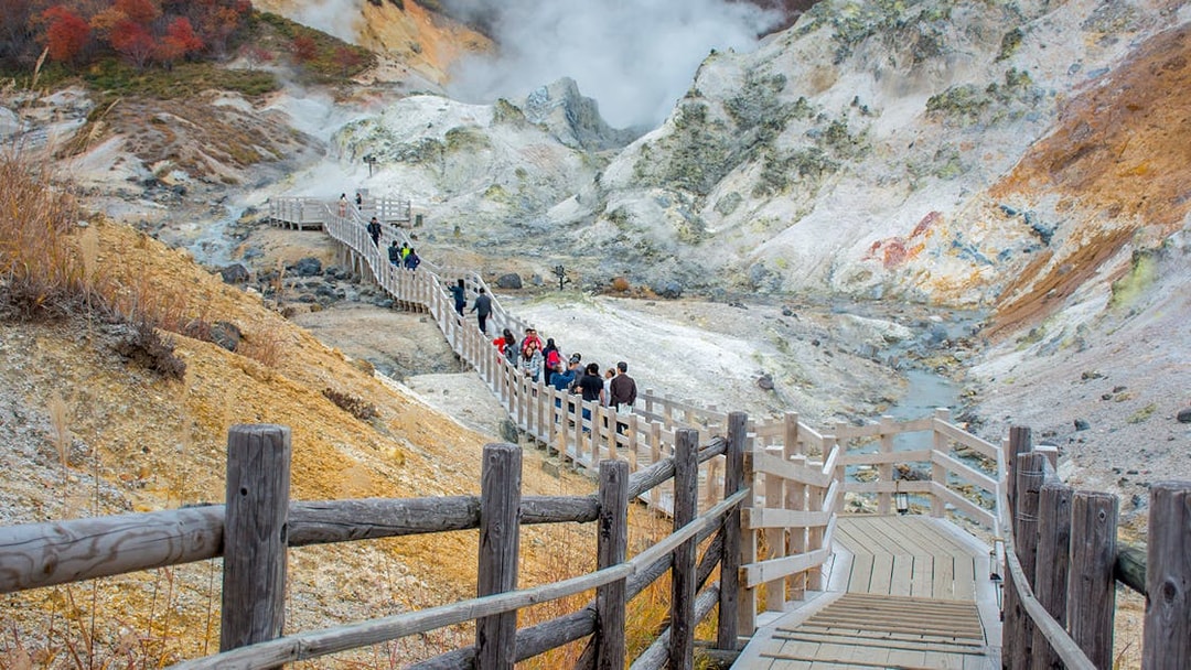 Visitors walking on a wooden path through Hell Valley in Noboribetsu, Japan.