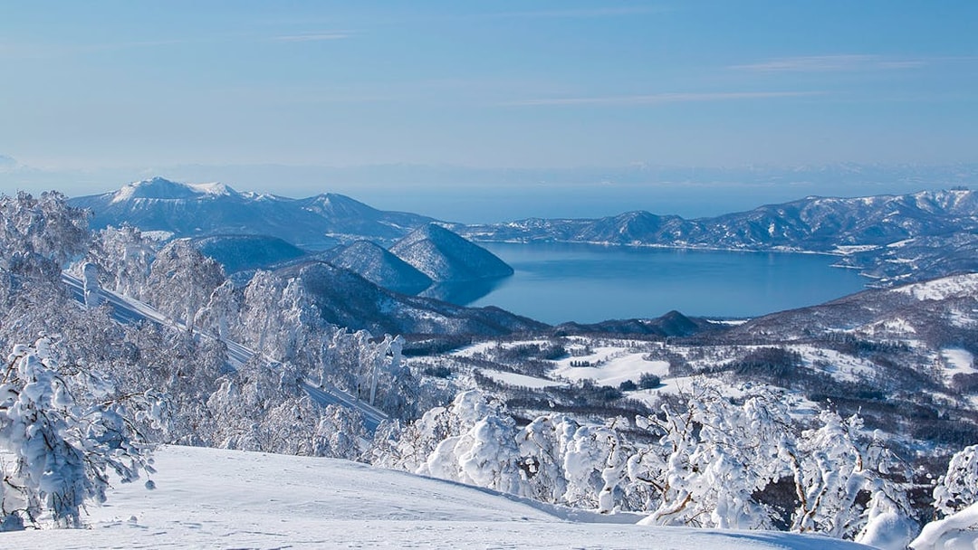 Snow-covered landscape with Lake Toya and surrounding mountains in Hokkaido, Japan.