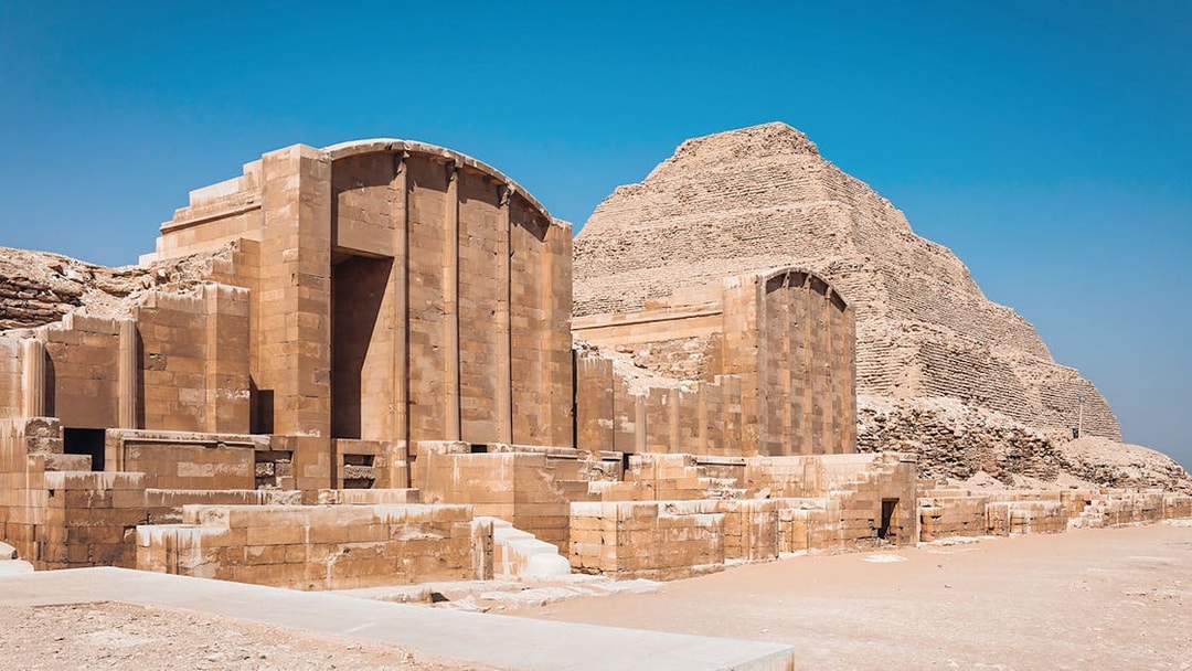 Sakkara Pyramid complex with ancient stone structures under a clear blue sky.