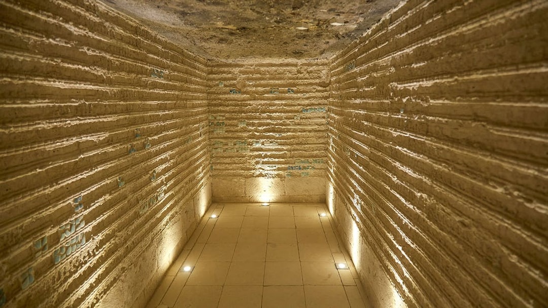 Corridor inside the Step Pyramid of Djoser, Saqqara, Egypt, with illuminated stone walls.