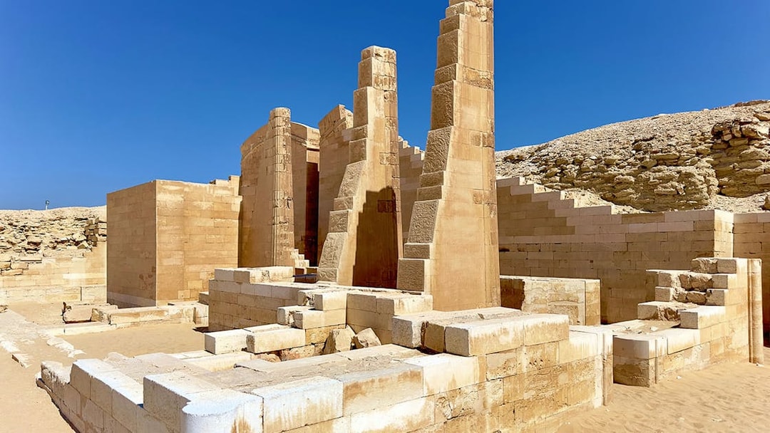 Ancient ruins of a temple in Memphis, Egypt, with stone columns and desert backdrop.