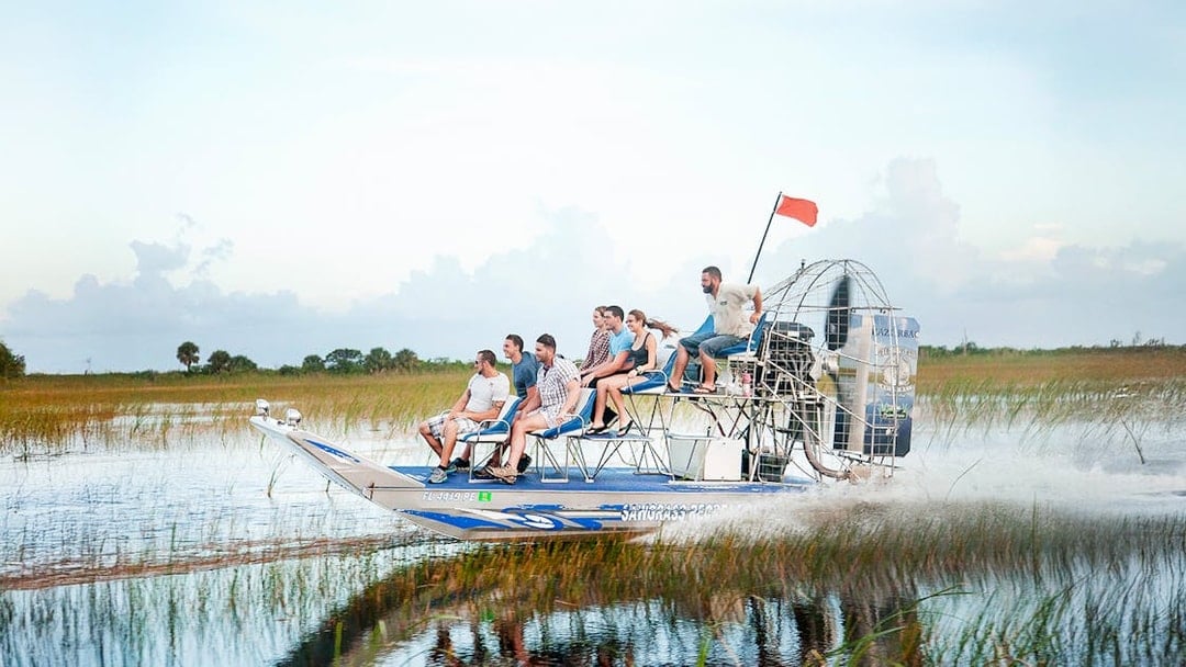 Airboat gliding through Everglades at Sawgrass Recreation Park with passengers.