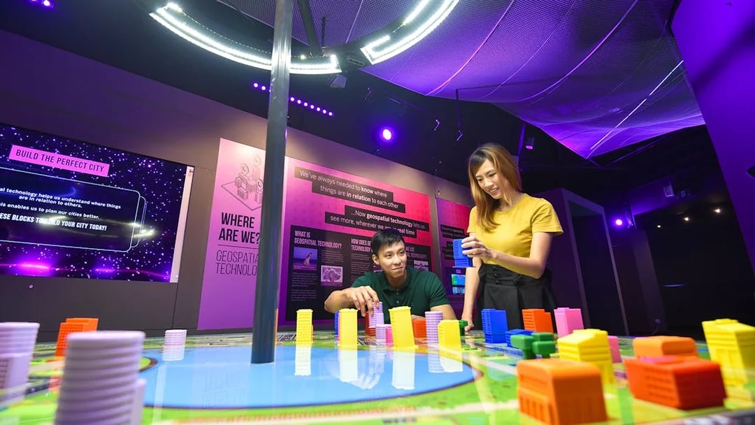 Visitors engaging with interactive geospatial technology exhibit at Science Centre Singapore.