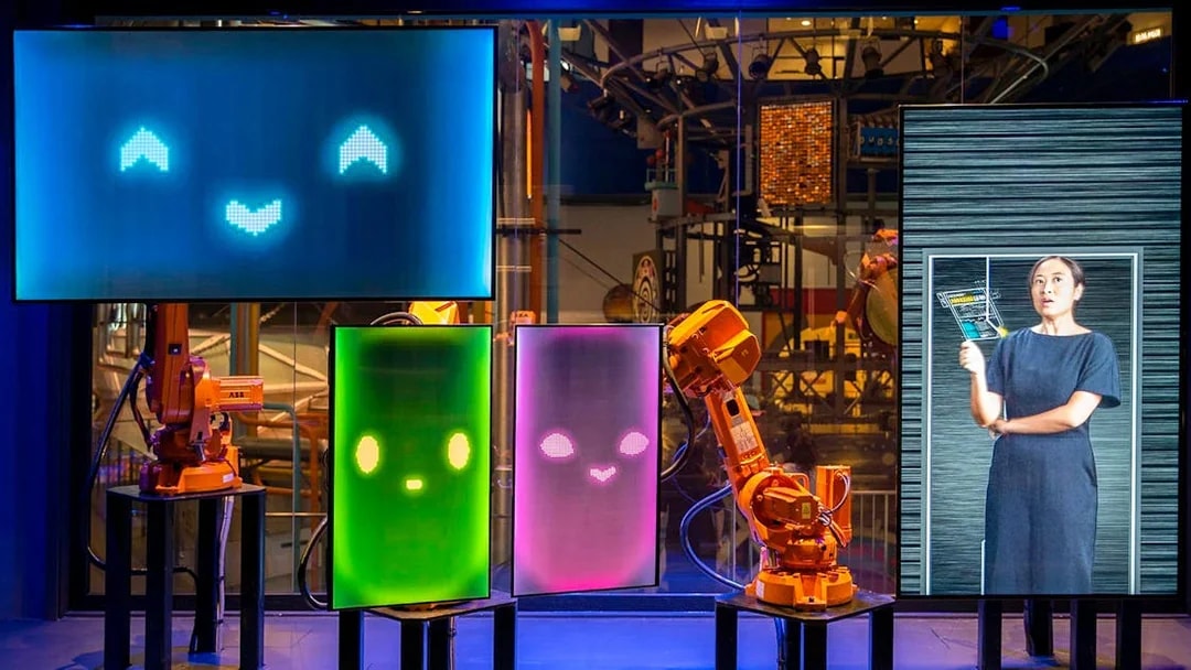 Interactive robot exhibit at Science Centre Singapore with digital screens and robotic arms.