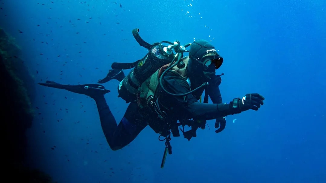 Scuba divers exploring underwater in the Gulf of Catania.