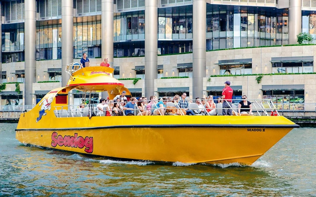 Tourists enjoying Sea Dog Cruise on Lake Michigan near city buildings.