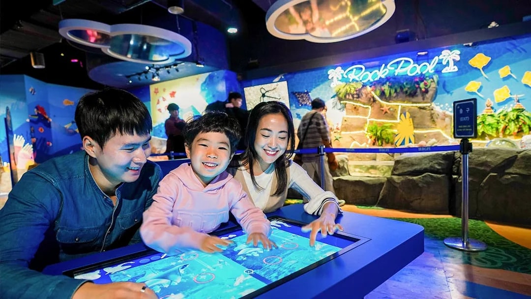 Visitors enjoying interactive display at SEA LIFE Busan Aquarium.
