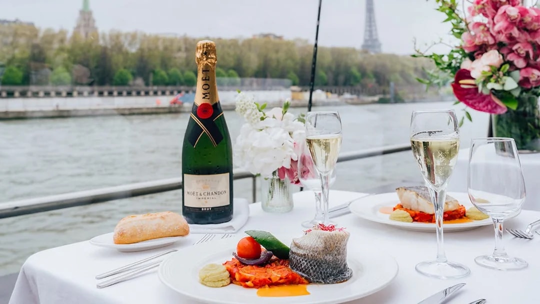 Champagne and gourmet meal on Seine River cruise with Eiffel Tower view.