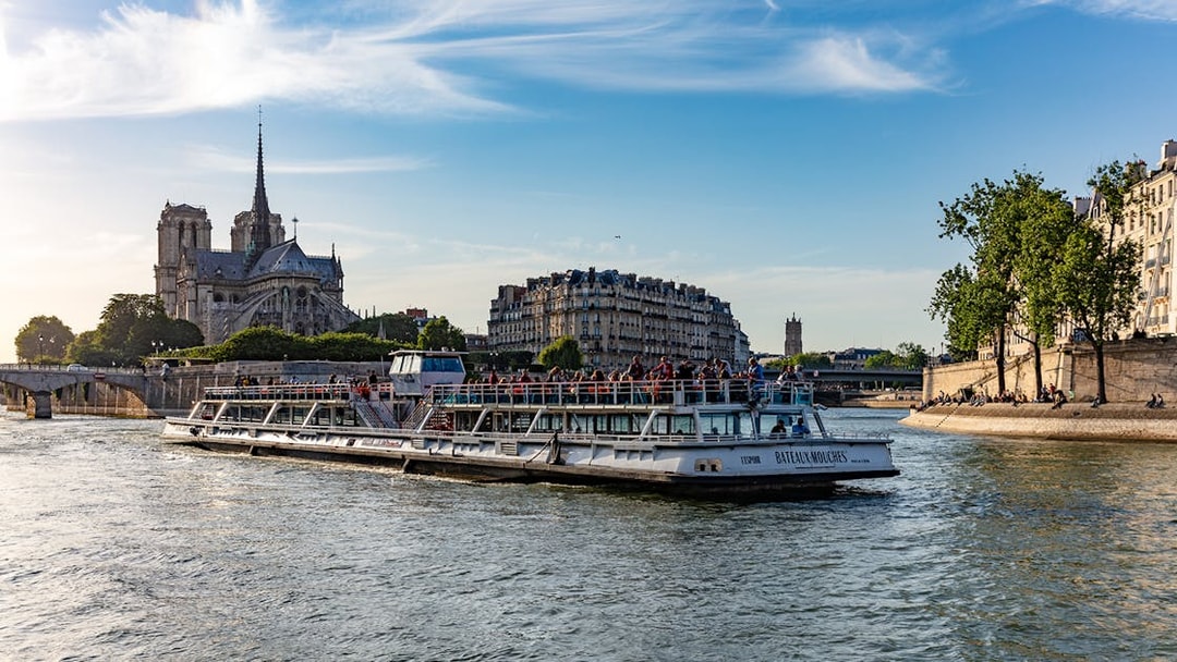 Bateaux Mouches cruising by Notre Dame Cathedral on the Seine River in Paris.