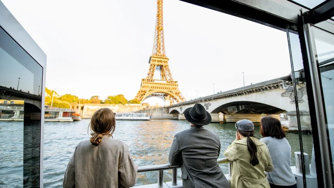 Family enjoying Seine River cruise with view of Eiffel Tower in Paris.