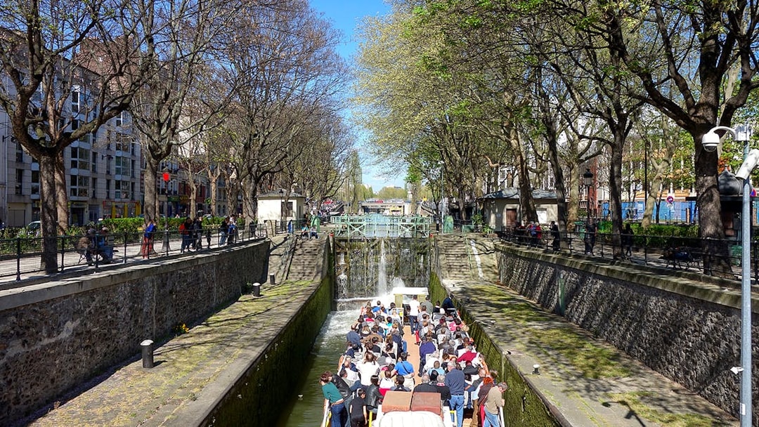 Boat tour on Canal Saint-Martin in Paris, passing through a lock with people on board.