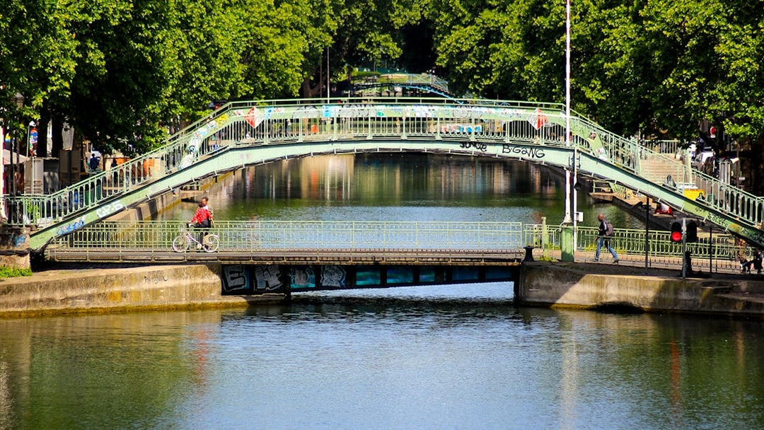 Canal Saint-Martin bridge in Paris with cyclist and pedestrian crossing.
