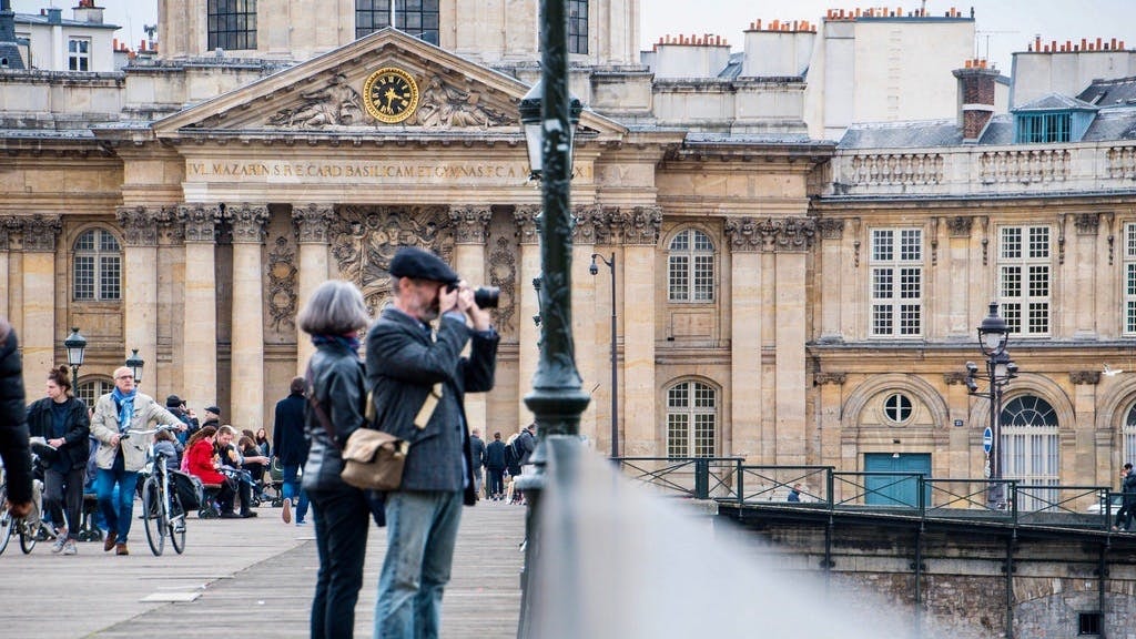 Tourists on a bridge near the Institut de France in Paris during a Seine River Cruise and City Tour.