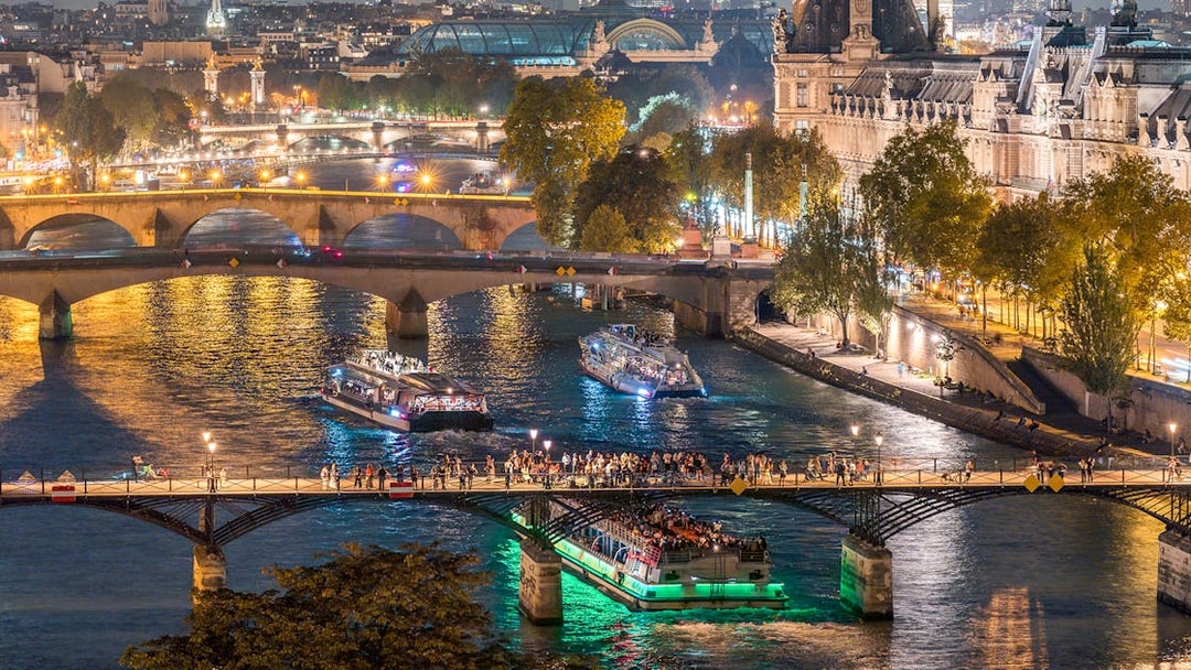 Seine River dinner cruise with live music passing under Paris bridges at night.