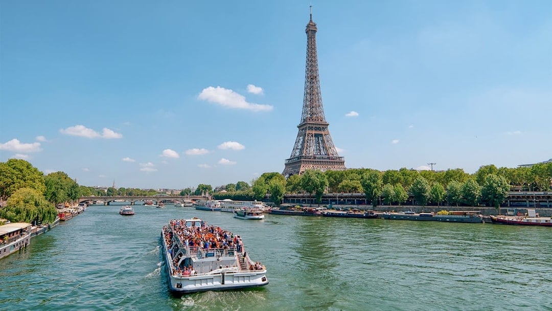 Seine River cruise boat near Eiffel Tower, Paris, during morning tour.