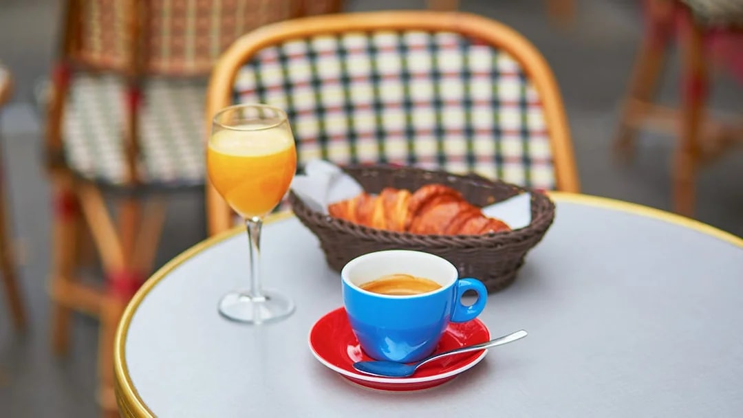 Coffee, orange juice, and croissants on a table during a Seine River cruise breakfast in Paris.