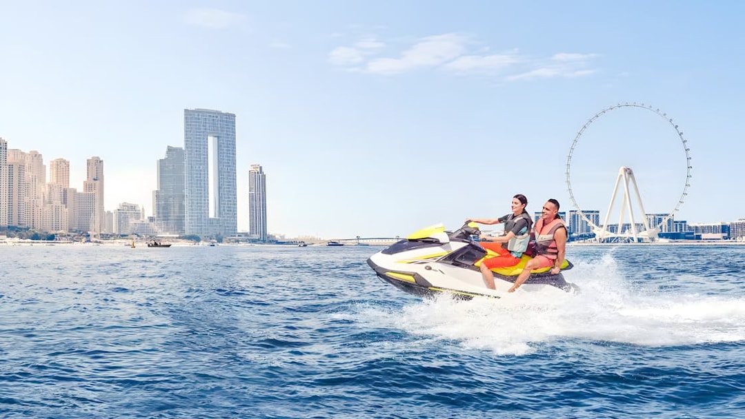 Jet ski riders near Burj Al Arab with Dubai skyline in background.
